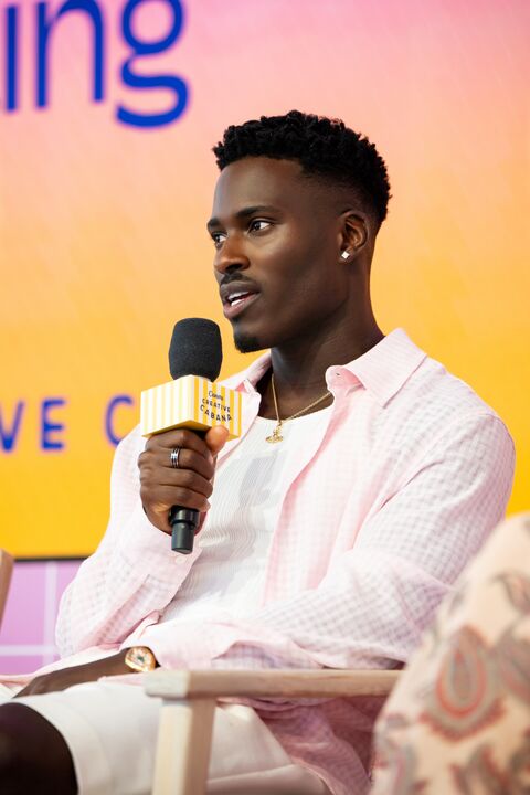 Creator speaking on stage with a microphone at an Atinuda event